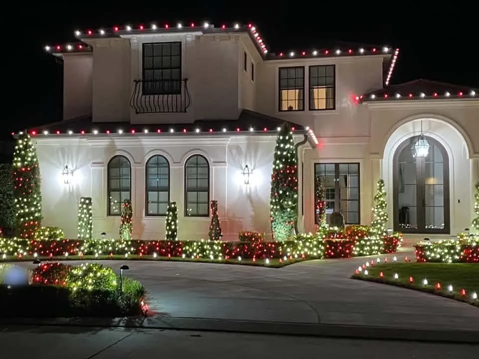 Red and white roofline lights with wrapped topiaries and hedges
