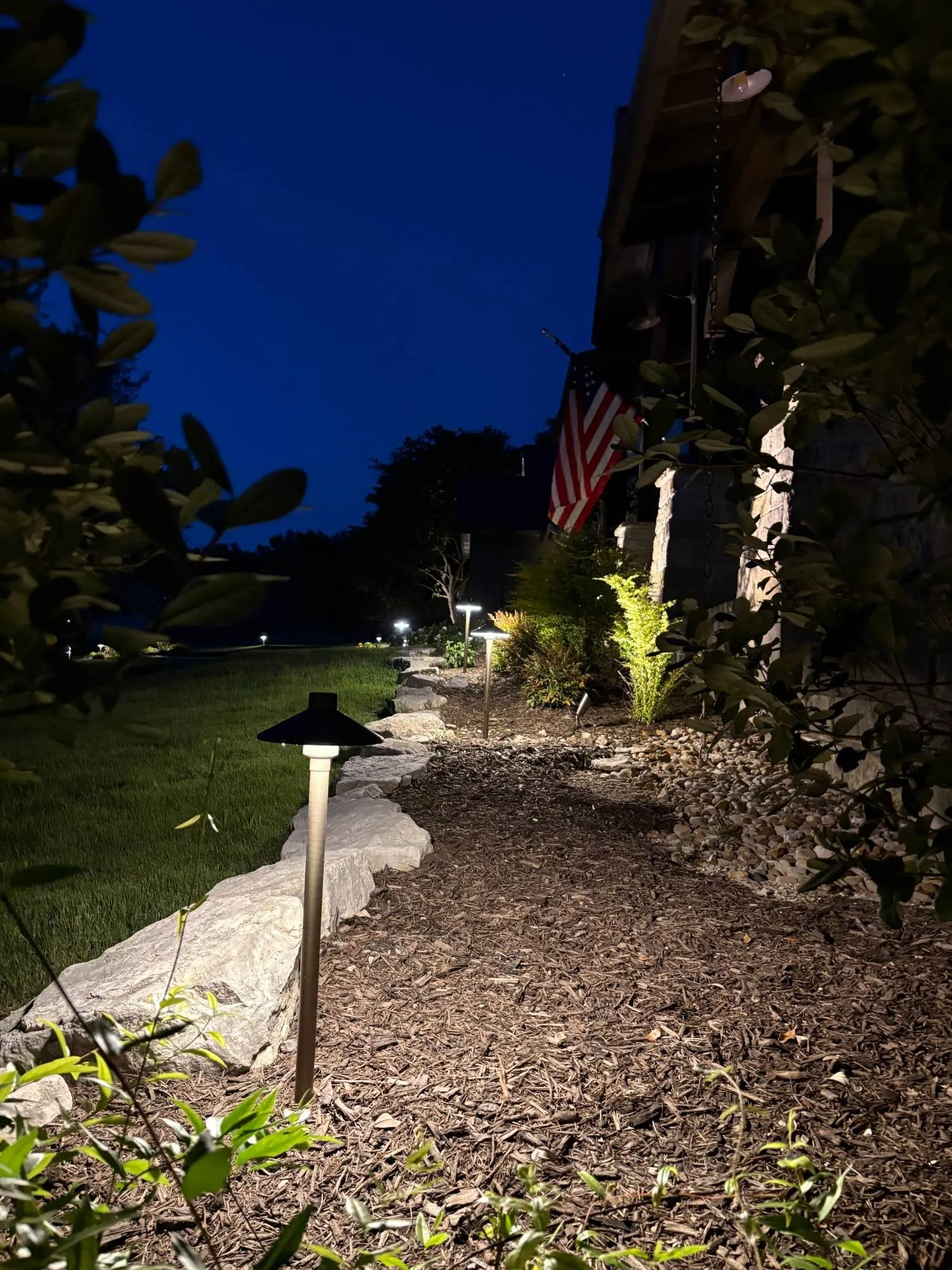 Brass path lights along a garden bed edged with limestone