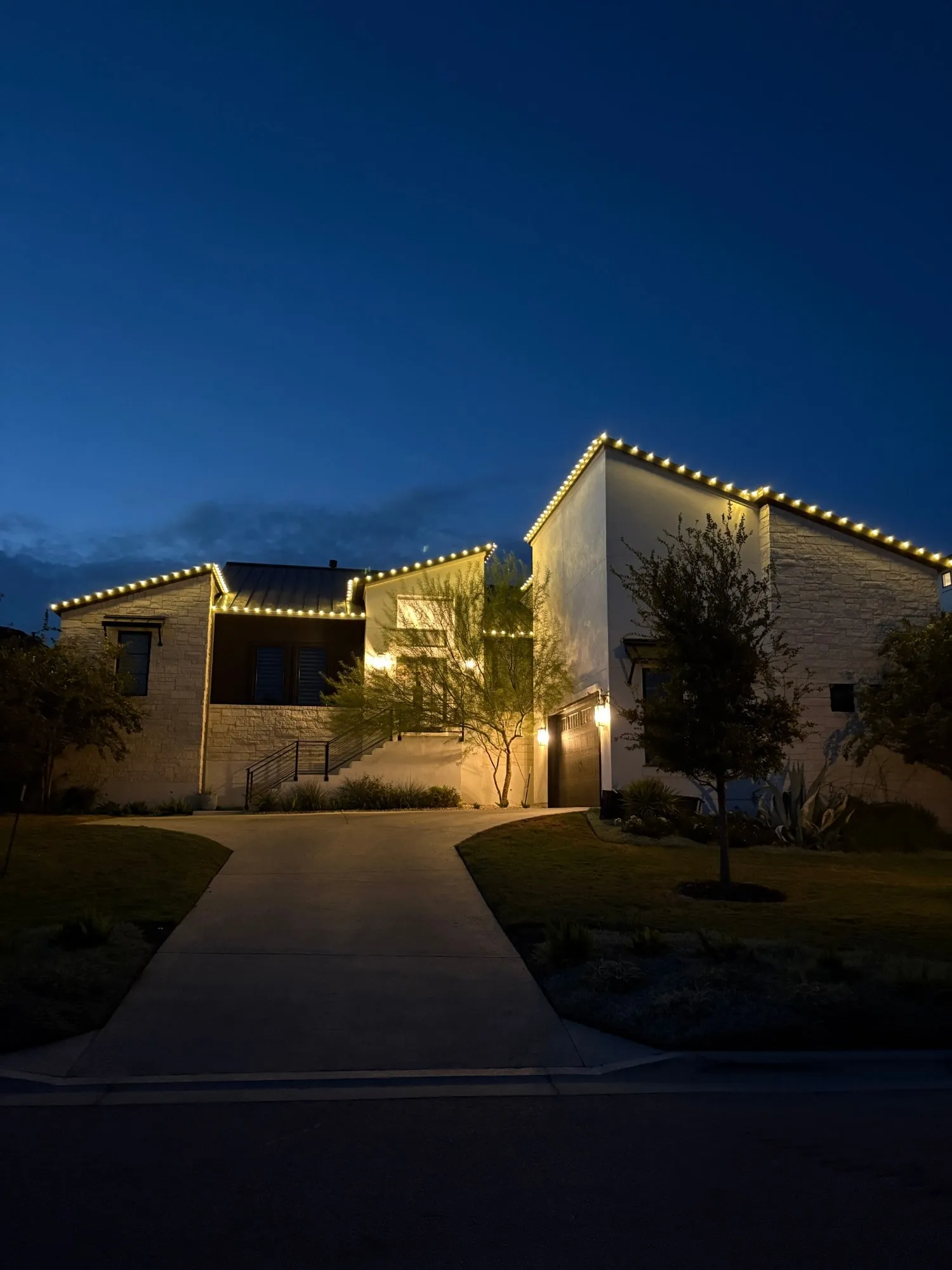 Warm white roofline lighting on a modern stone home